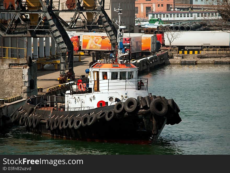 Tug boat in the port and cranes in the background