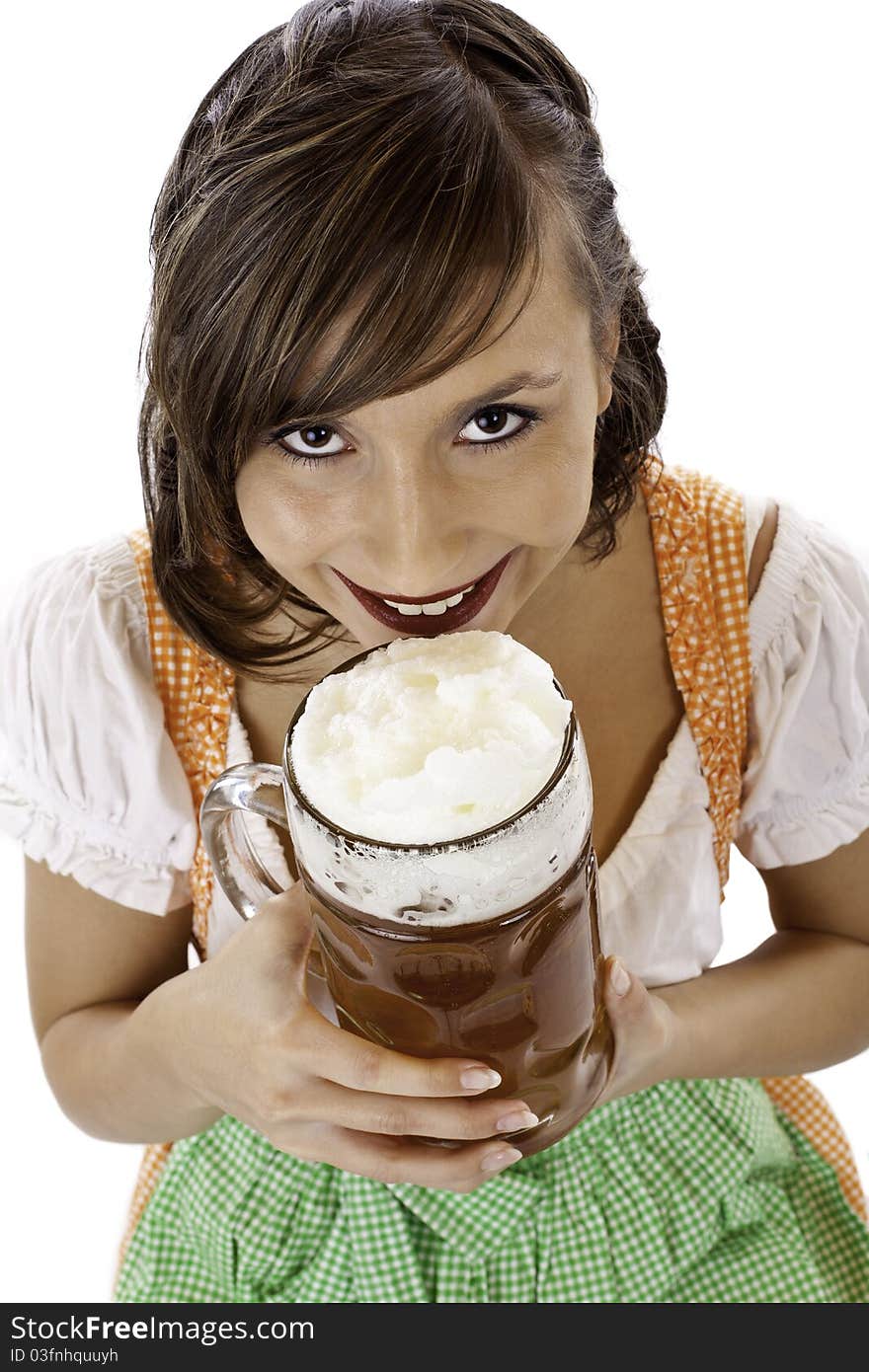 Beautiful young woman with dirndl drinks Oktoberfest beer stein. Isolated on white background.