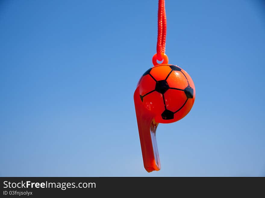 A referees whistle against a blue sky. A referees whistle against a blue sky