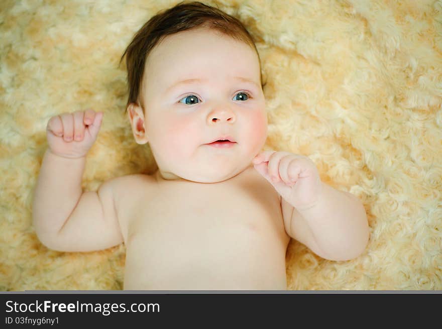 Beautiful baby boy is lying in a bed.