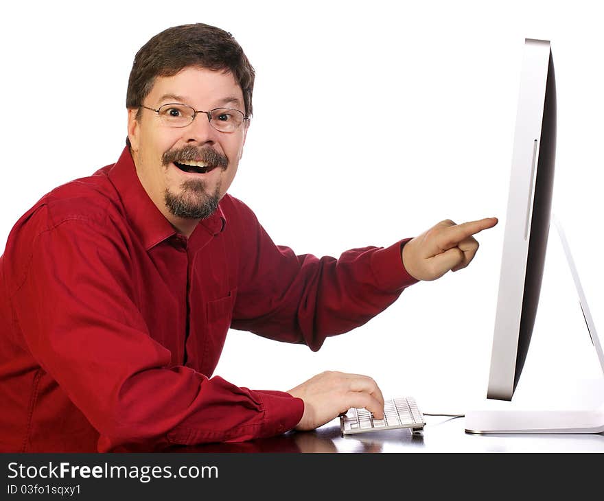 Casually dressed mature business man works and his computer while excitedly pointing out something important on the computer. Casually dressed mature business man works and his computer while excitedly pointing out something important on the computer