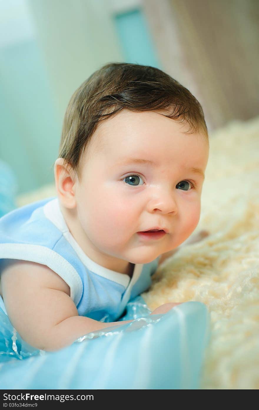 Beautiful baby boy is lying in a bed.