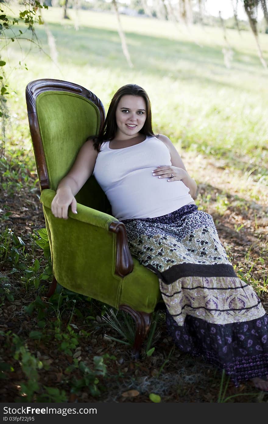 Pregnant woman sitting outside in vintage chair.