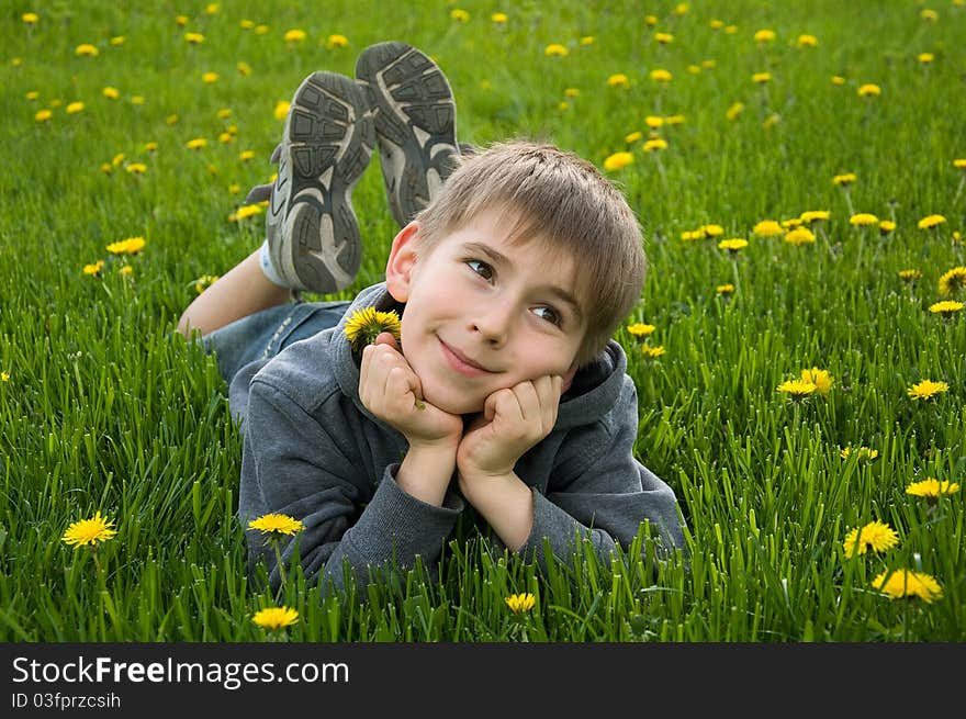 Boy lying on dandelion meadow