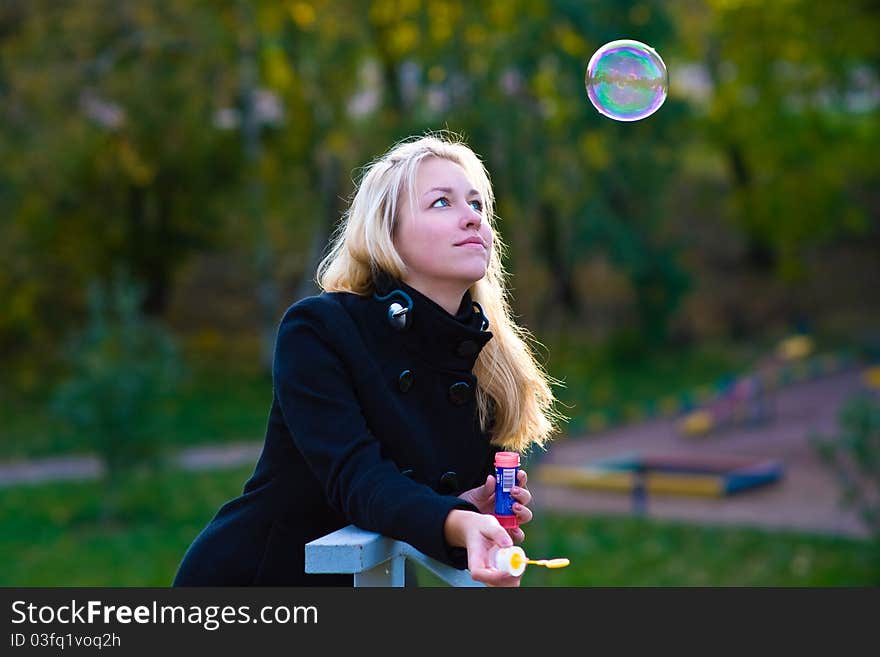 A teenage girl blow bubbles, a large multi-colored bubble flies high and she looks at him. A teenage girl blow bubbles, a large multi-colored bubble flies high and she looks at him