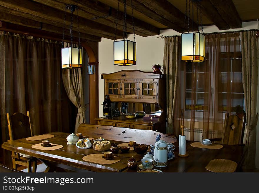 The interior dining room in the cottage - a wooden structure protected by a tree shaded lamps. The interior dining room in the cottage - a wooden structure protected by a tree shaded lamps