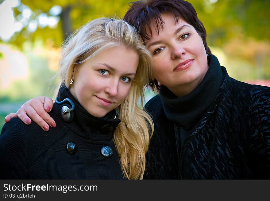 Mom and teen girl with long blond hair standing arm in arm. Mom and teen girl with long blond hair standing arm in arm