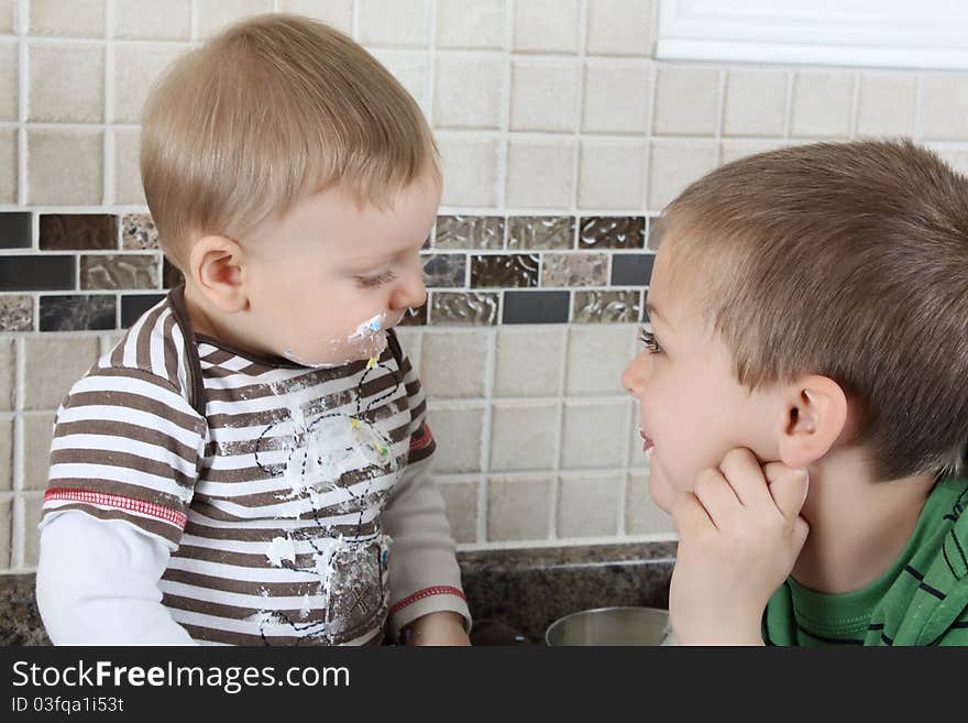 Brothers on kitchen counter eating icing sugar. Brothers on kitchen counter eating icing sugar