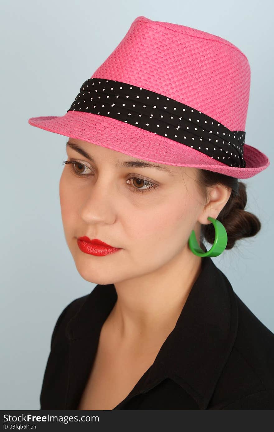 Brunette female wearing a pink hat and green earrings