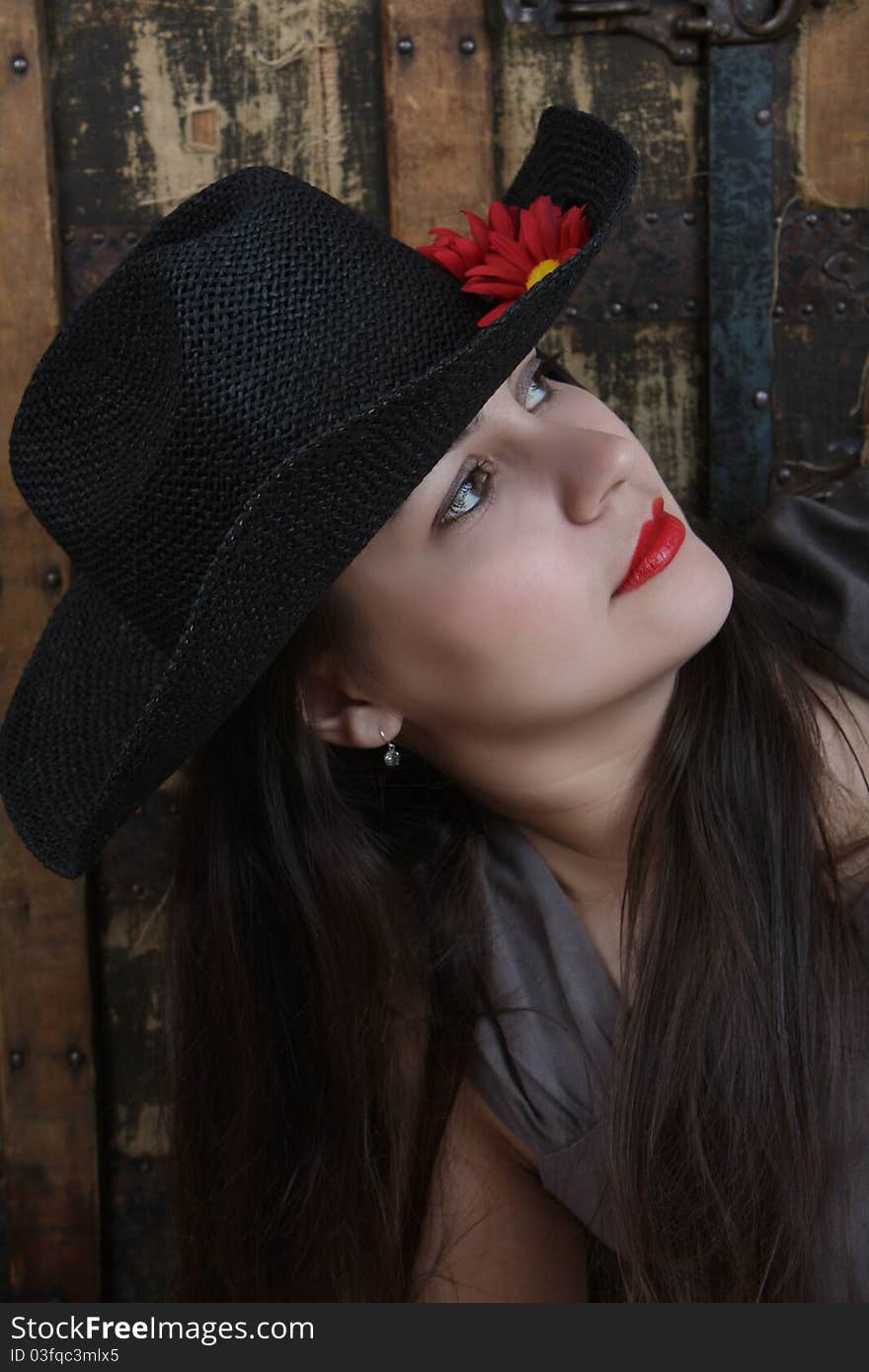 Brunette female with hat in front of antique trunk. Brunette female with hat in front of antique trunk