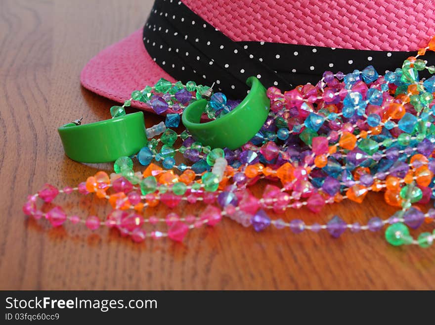 Costume Jewelery and pink hat on wooden table. Costume Jewelery and pink hat on wooden table