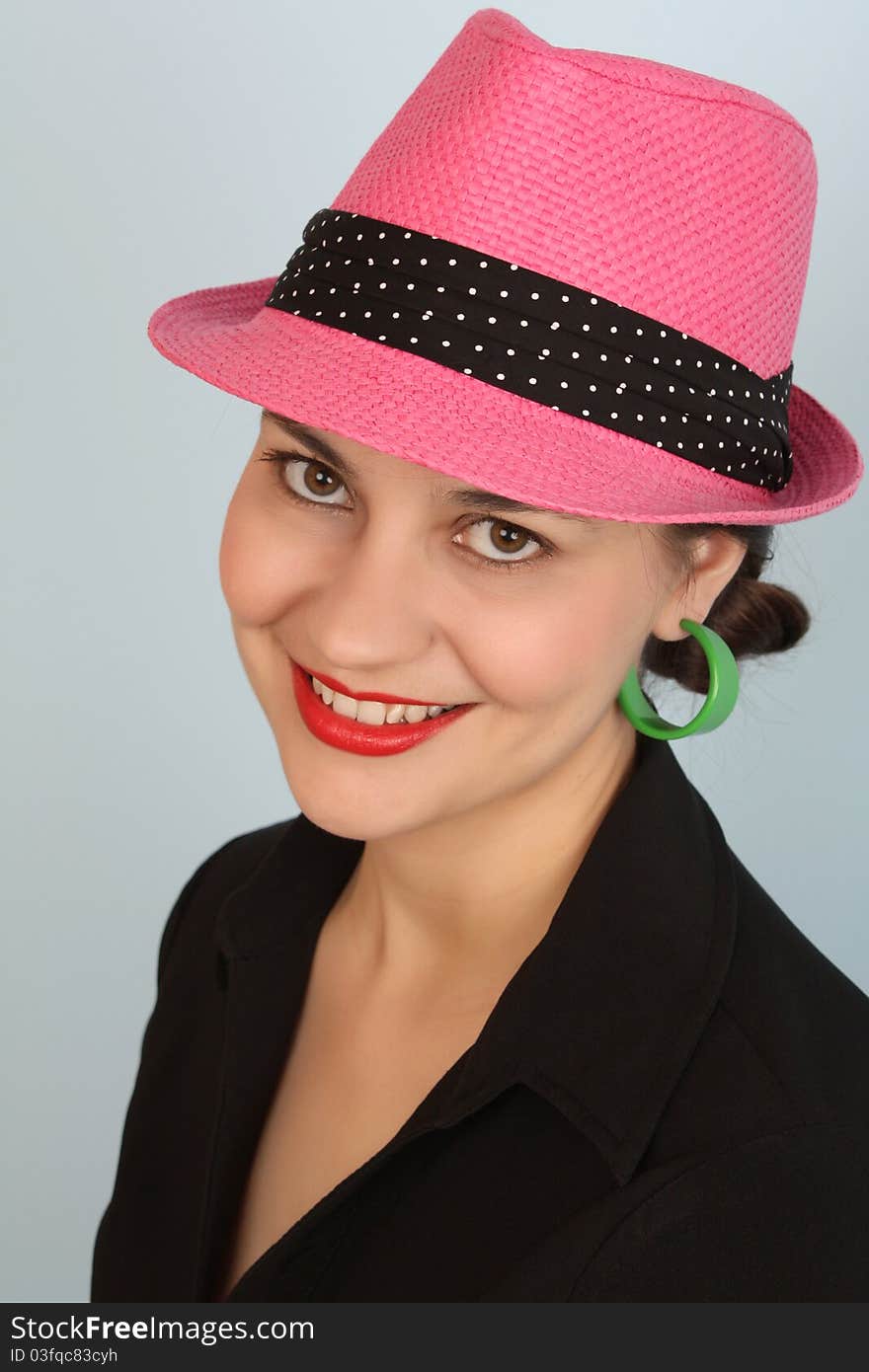 Brunette female wearing a pink hat and green earrings