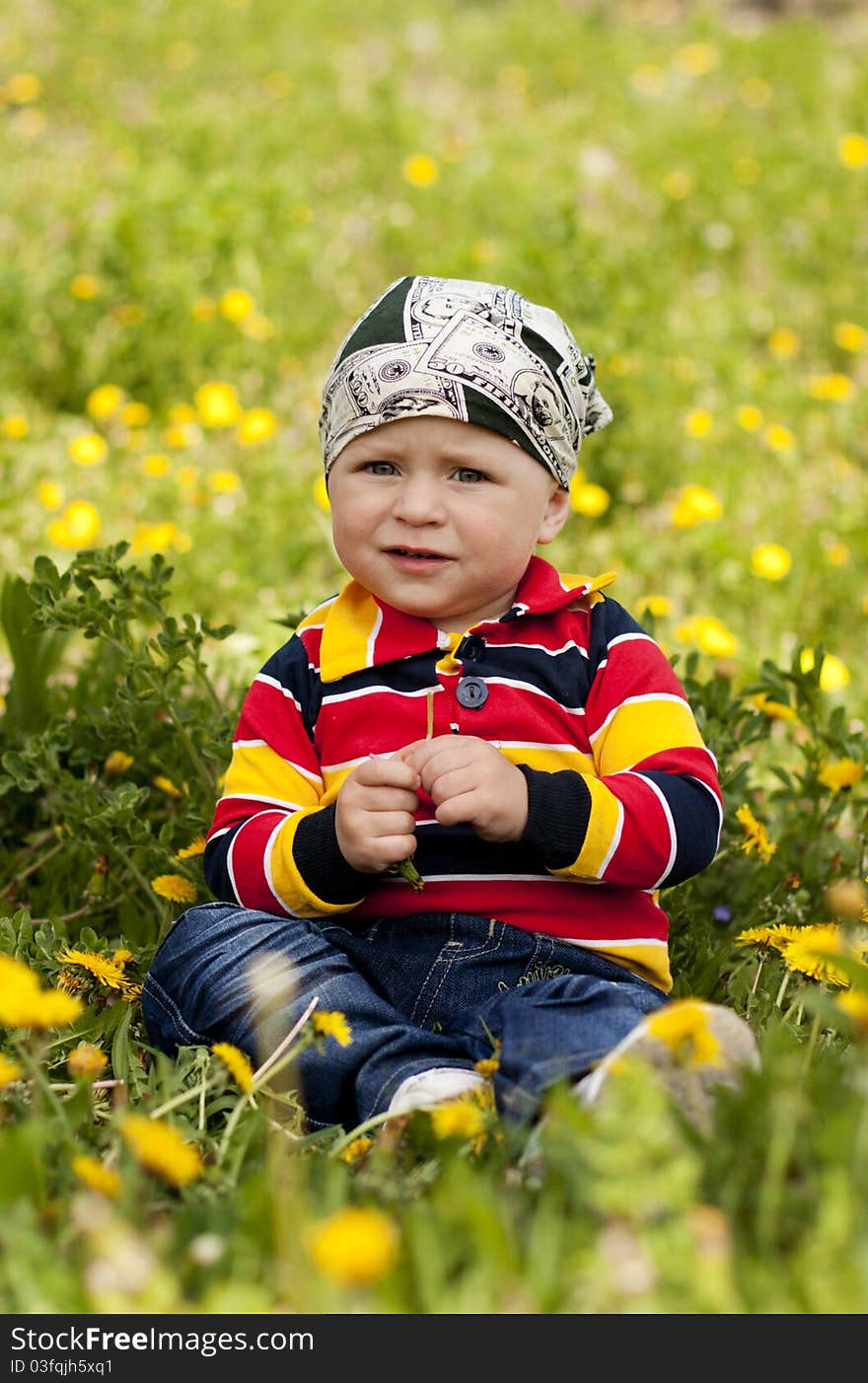 Little boy sitting on green grass in the reflection