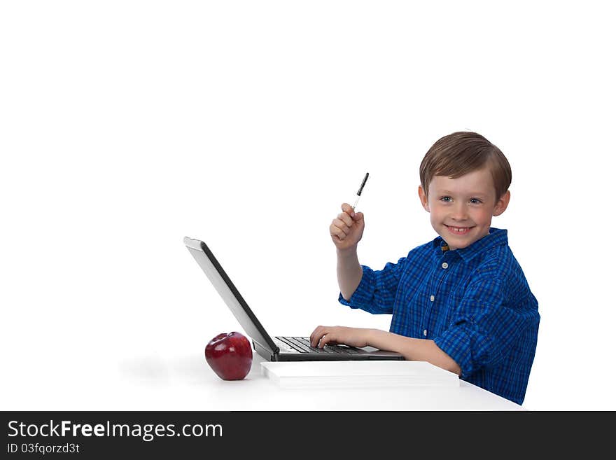 Seven-year-old cute caucasian boy working on laptop, raising his hand, holding pen on white background, smiling and looking up. Seven-year-old cute caucasian boy working on laptop, raising his hand, holding pen on white background, smiling and looking up