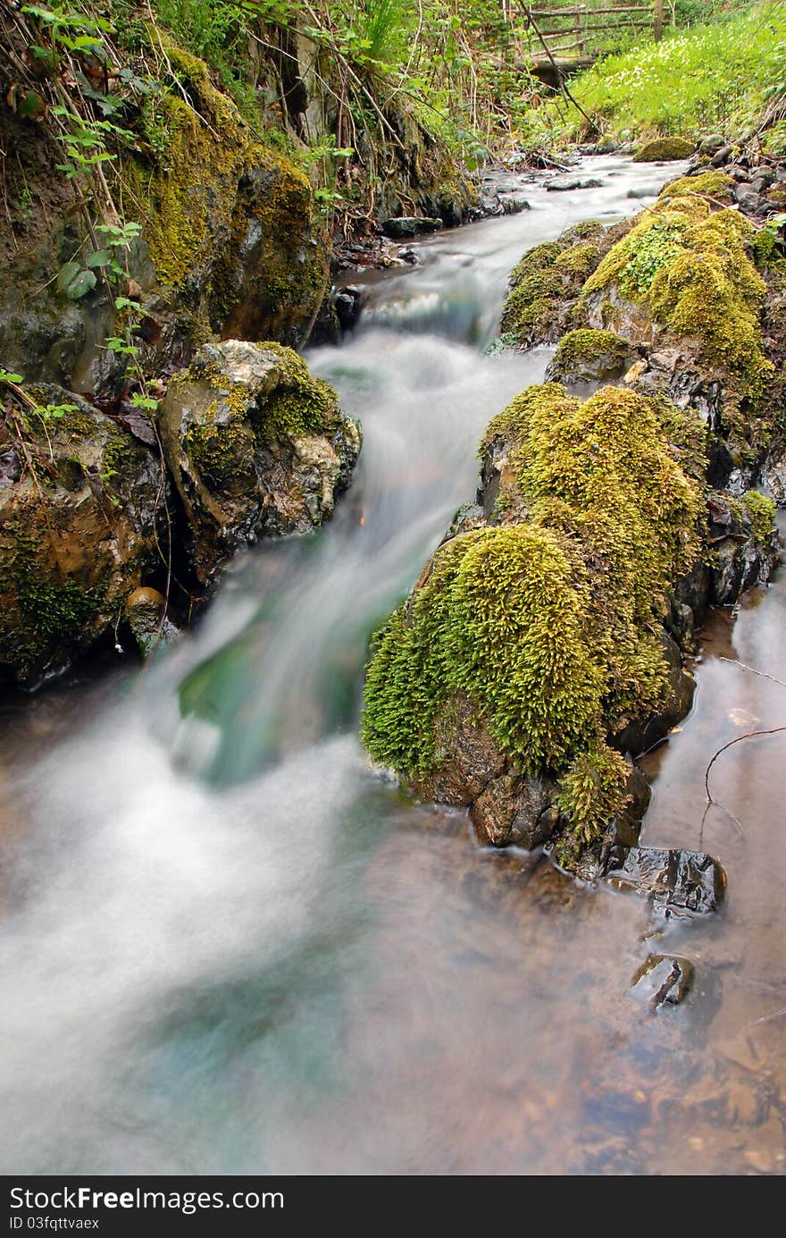 Stream between stones in green forest landscape. Stream between stones in green forest landscape