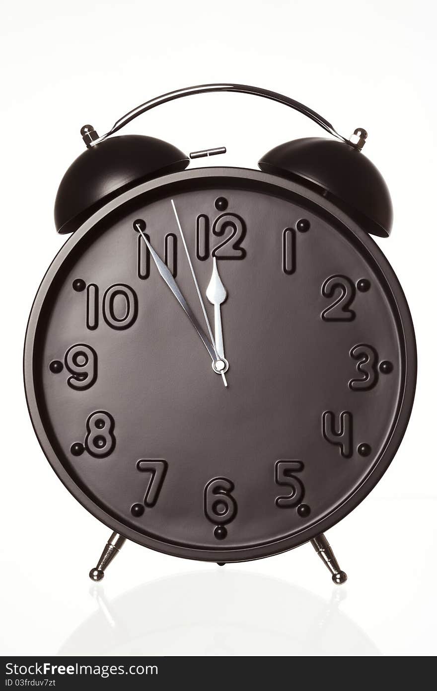 Black alarm clock showing 5 minutes to twelve, isolated on white background. Black alarm clock showing 5 minutes to twelve, isolated on white background.