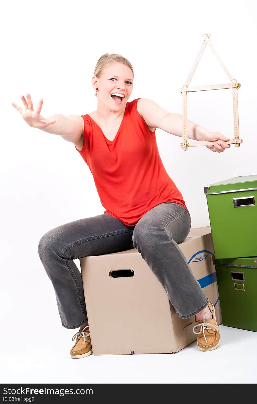 Young woman with a house symbol sits on moving box