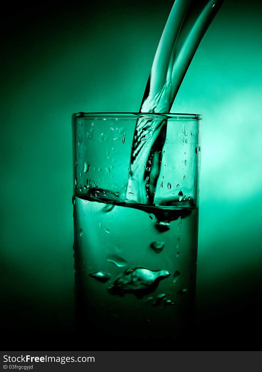 Glass beaker with water on a green background