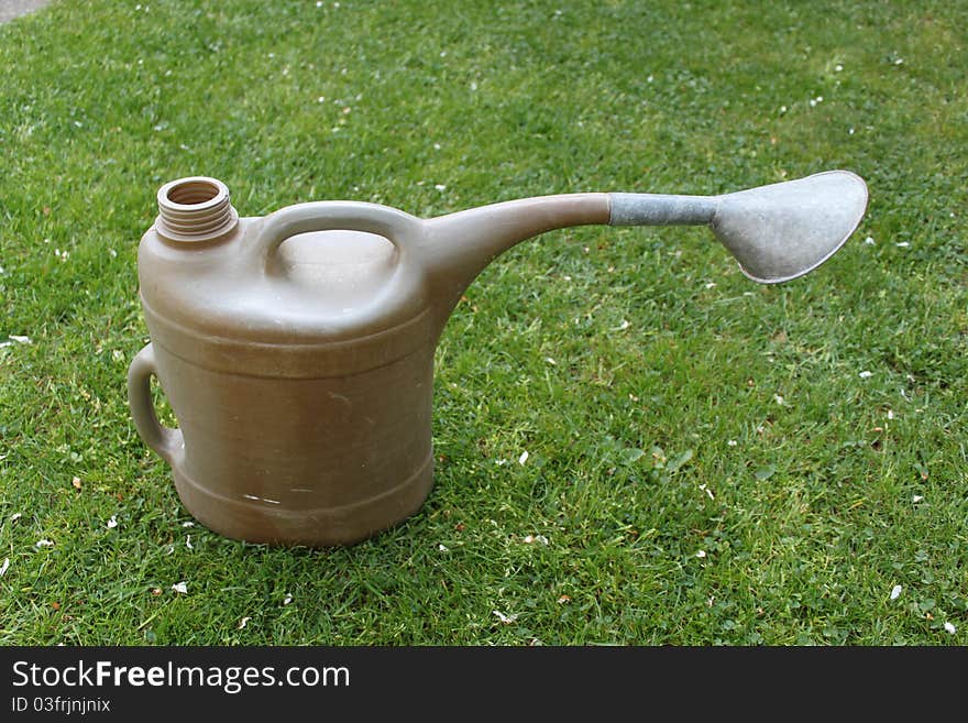 Watering can lying in the grass in spring. Watering can lying in the grass in spring