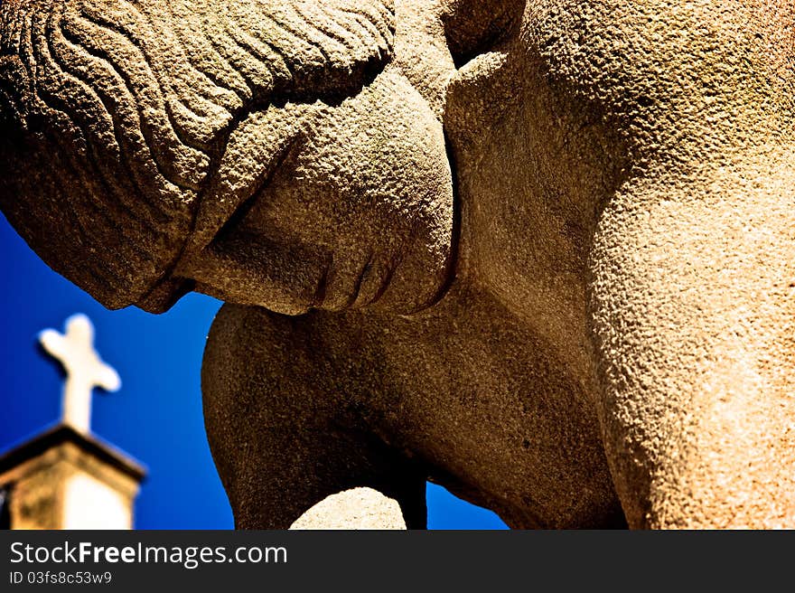 Sculpture of man praying with cross