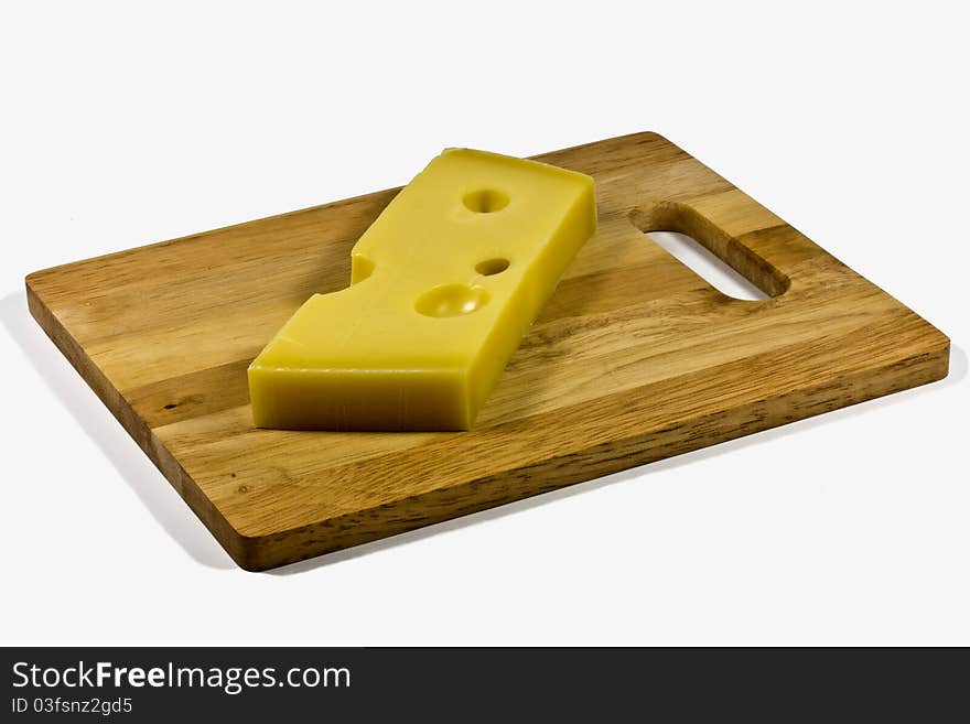 A wedge of emmental cheese on a wooden board