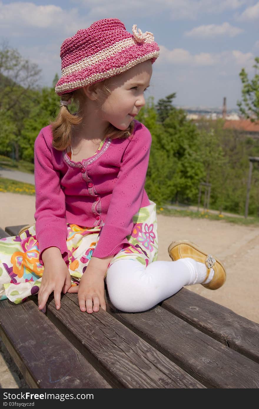 Little girl dressed in pink is sitting outdoor. Little girl dressed in pink is sitting outdoor.