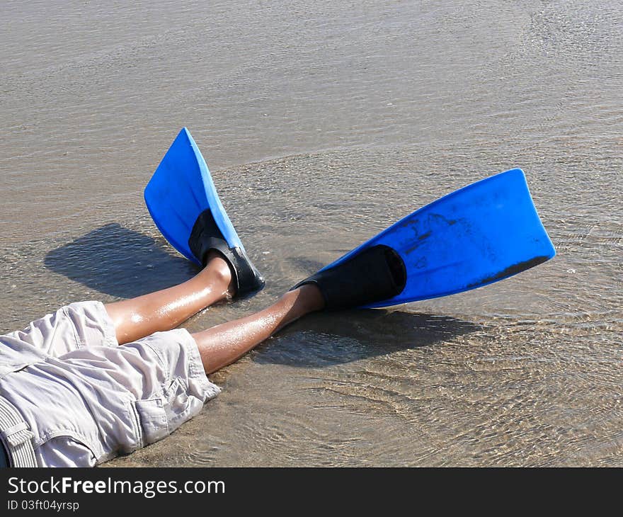 Boy s legs wearing swim fins on the beach