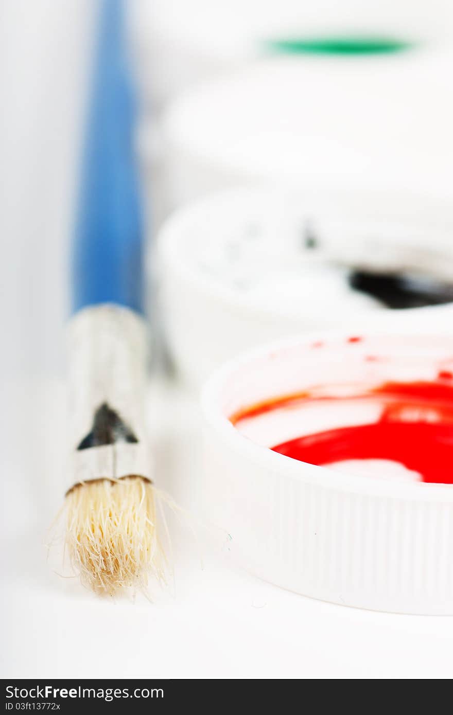 Macro view of brush and covers of gouache paint cans