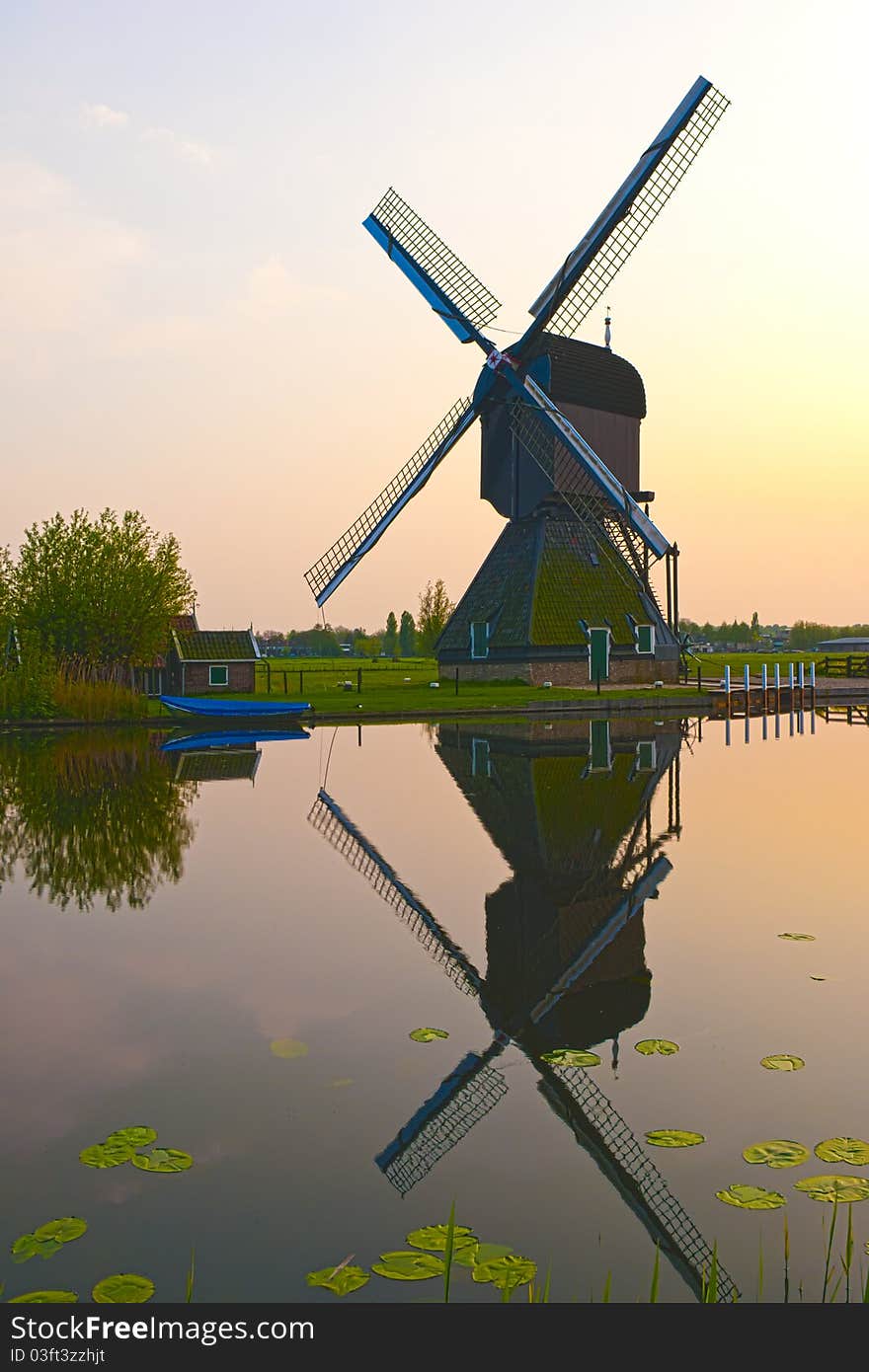 HDR image of a windmill in the evening sunset after the rain, casting a perfect reflection on the water in the canal. HDR image of a windmill in the evening sunset after the rain, casting a perfect reflection on the water in the canal.