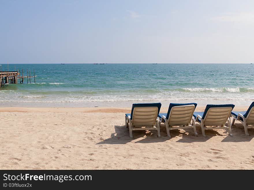 The empty beach, four chaise lounges and pier