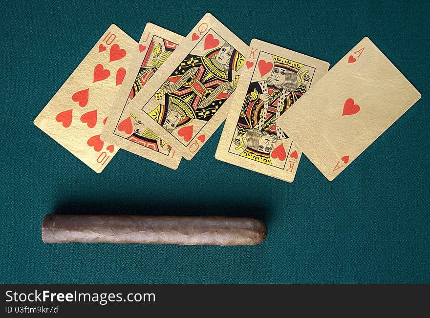 Cigar and playing cards on a green background.