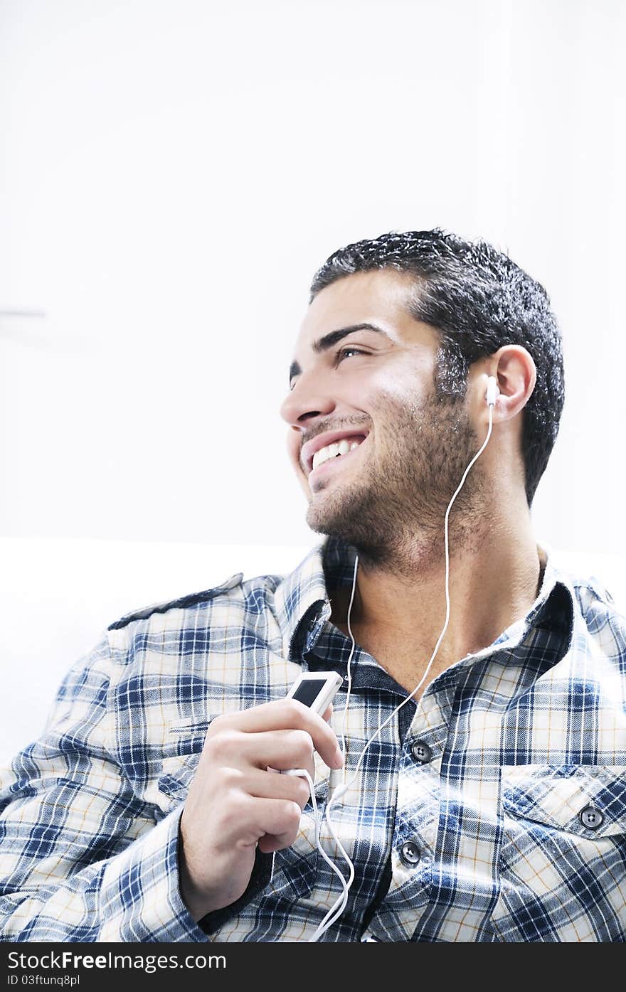 Young man listening music in home interior on the white background. Young man listening music in home interior on the white background