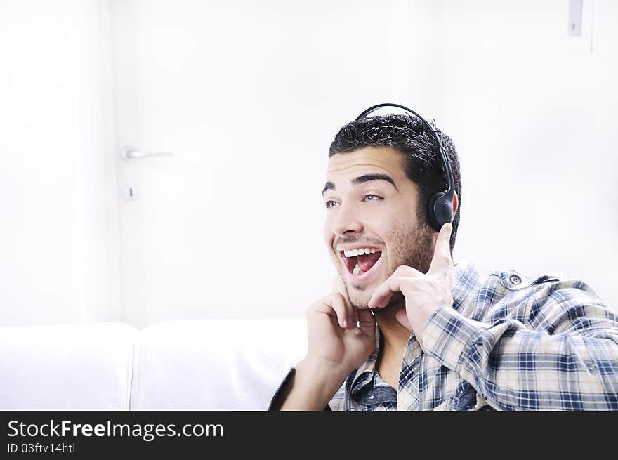 Young man listening music in home interior on the white background. Young man listening music in home interior on the white background