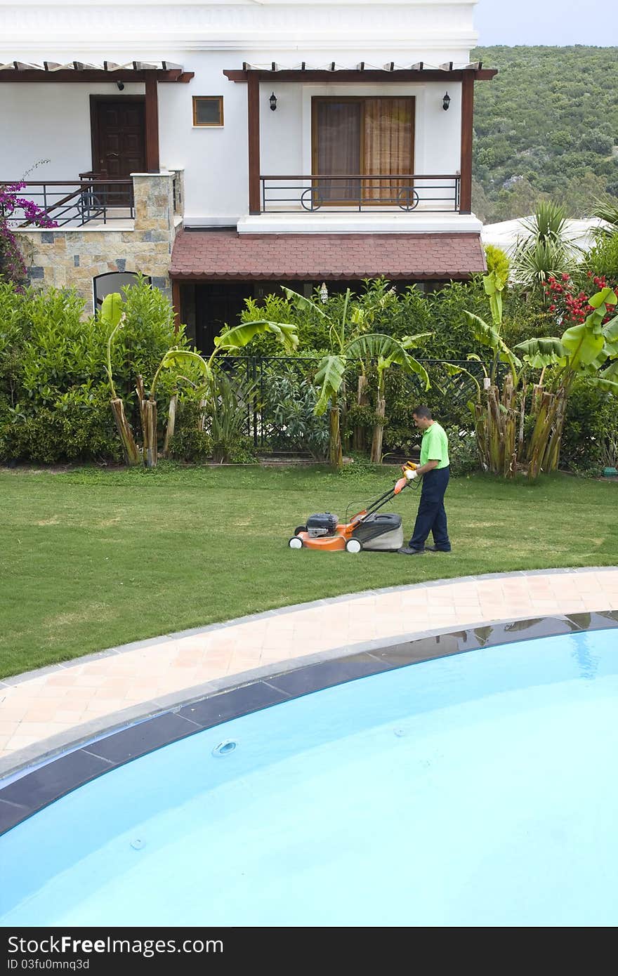 A gardener is cutting grass with machine. A gardener is cutting grass with machine