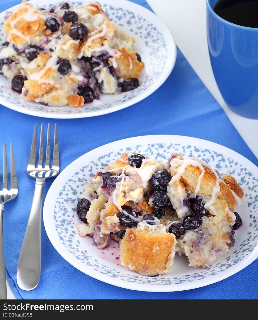 Two plates of blueberry pudding with forks and a cup of coffee. Two plates of blueberry pudding with forks and a cup of coffee