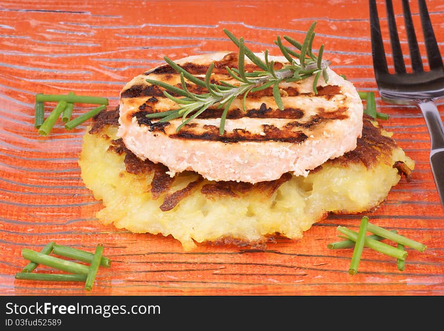 Roesti and grilled salmon with chives and rosemary over a glass dish