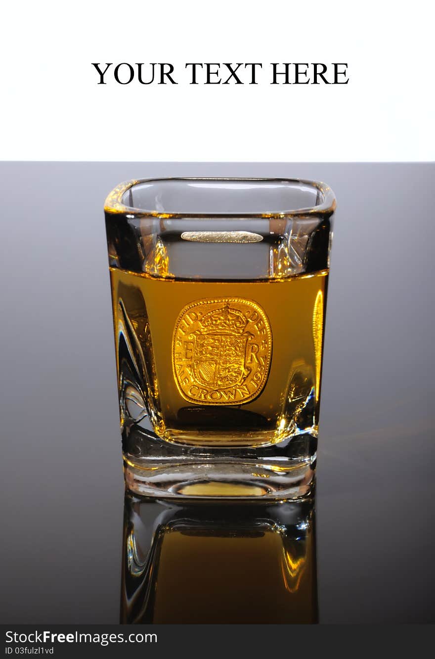 Old British coin Half Crown located behind the shot of whiskey