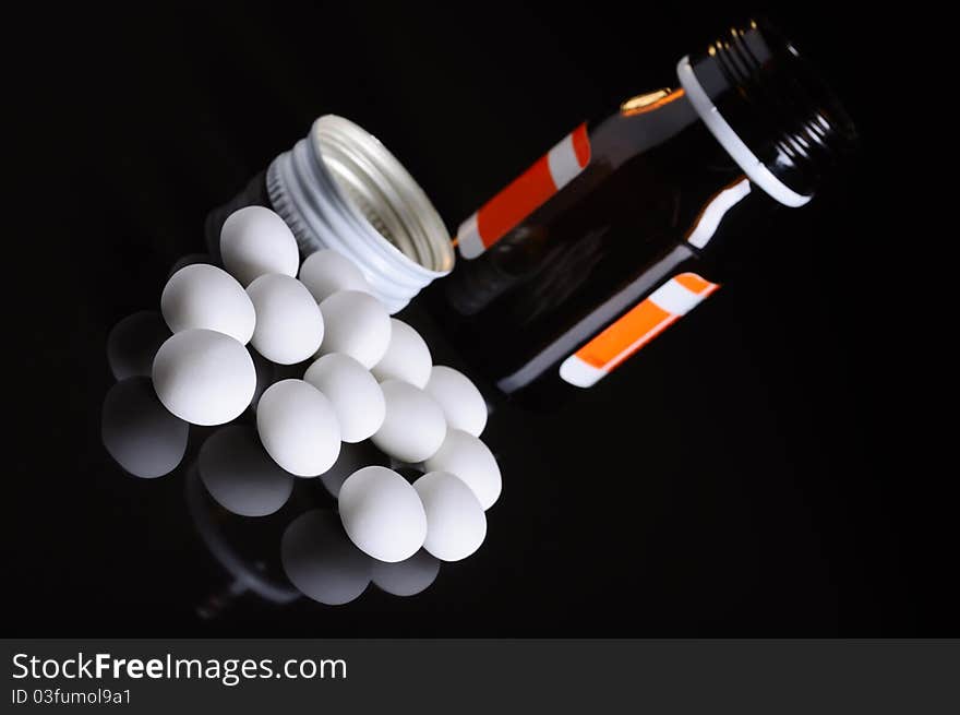 Pill bottle with whitepills on black background. Pill bottle with whitepills on black background