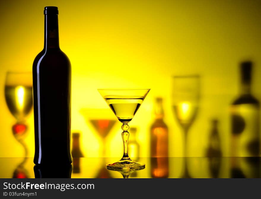 Dark bottle and glass on a background with the shadows of bottles