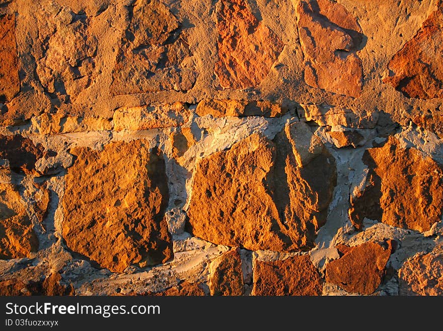 Ancient stone wall bathed in yellow light of the setting sun. Ancient stone wall bathed in yellow light of the setting sun