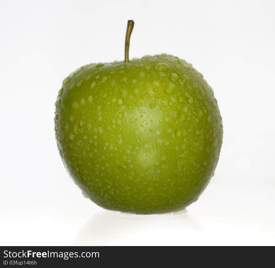 Green apple covered with water drops on a white background