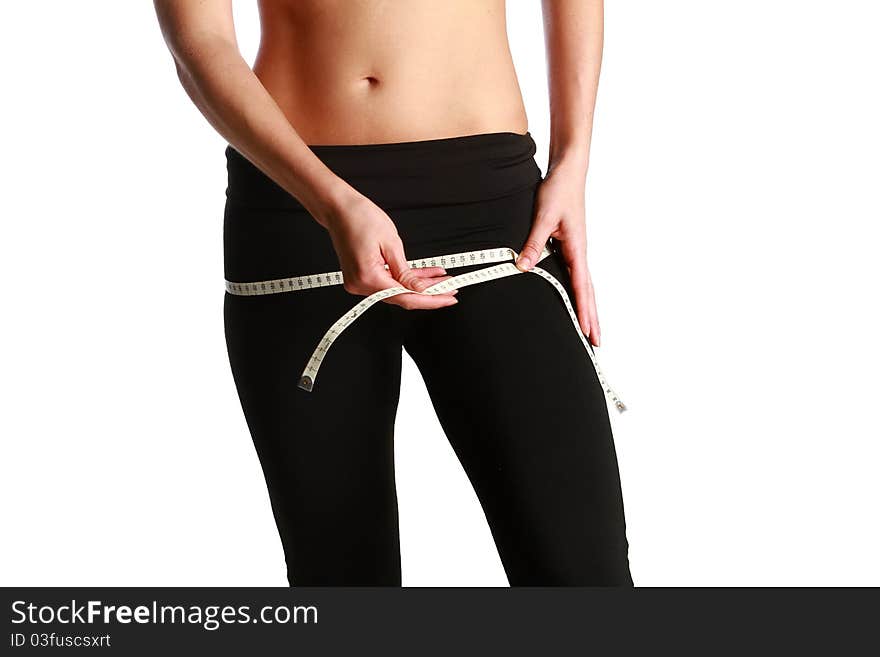 Photo of a fit and healthy young lady measuring her waist with a tape measure in centimeters and millimeters. She has her black gym exercise outfit on. Isolated image on white. Photo of a fit and healthy young lady measuring her waist with a tape measure in centimeters and millimeters. She has her black gym exercise outfit on. Isolated image on white.