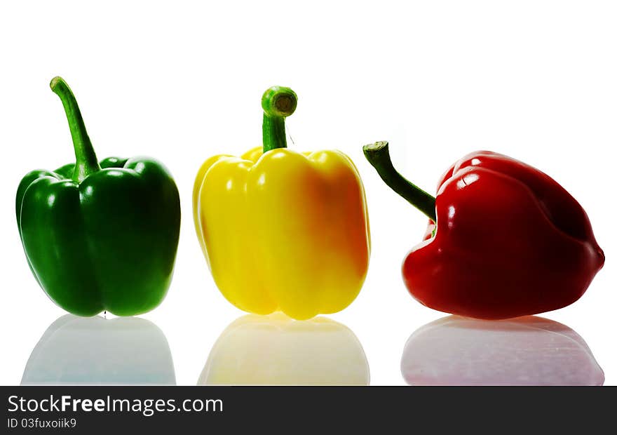 Three peppers, red, yellow, green, white background.