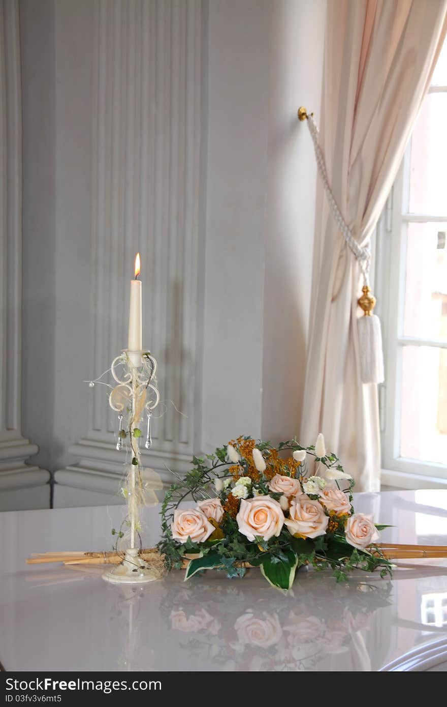 Burning candle on a white piano with flowers. Burning candle on a white piano with flowers