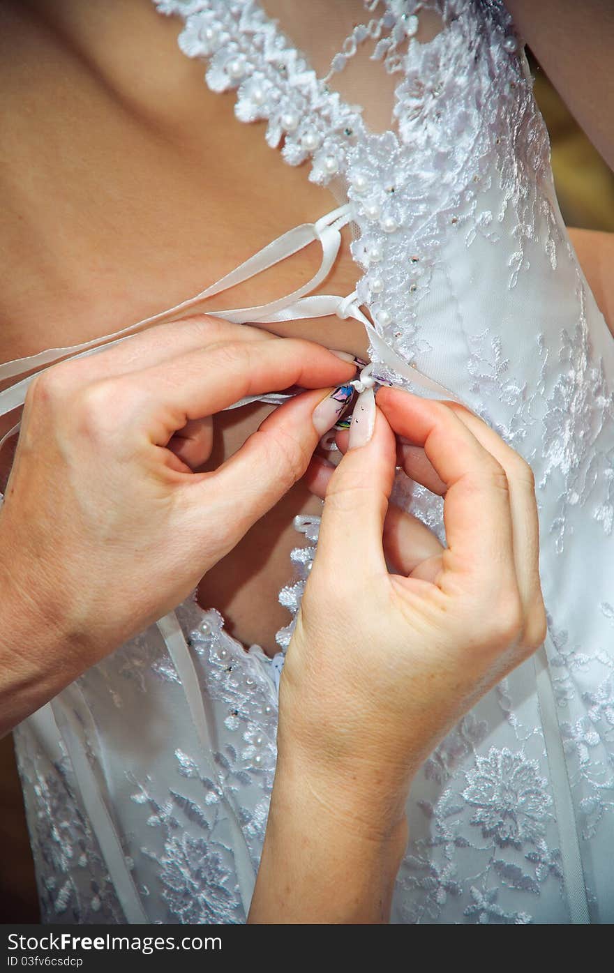 Hands helping to put on a white wedding dress