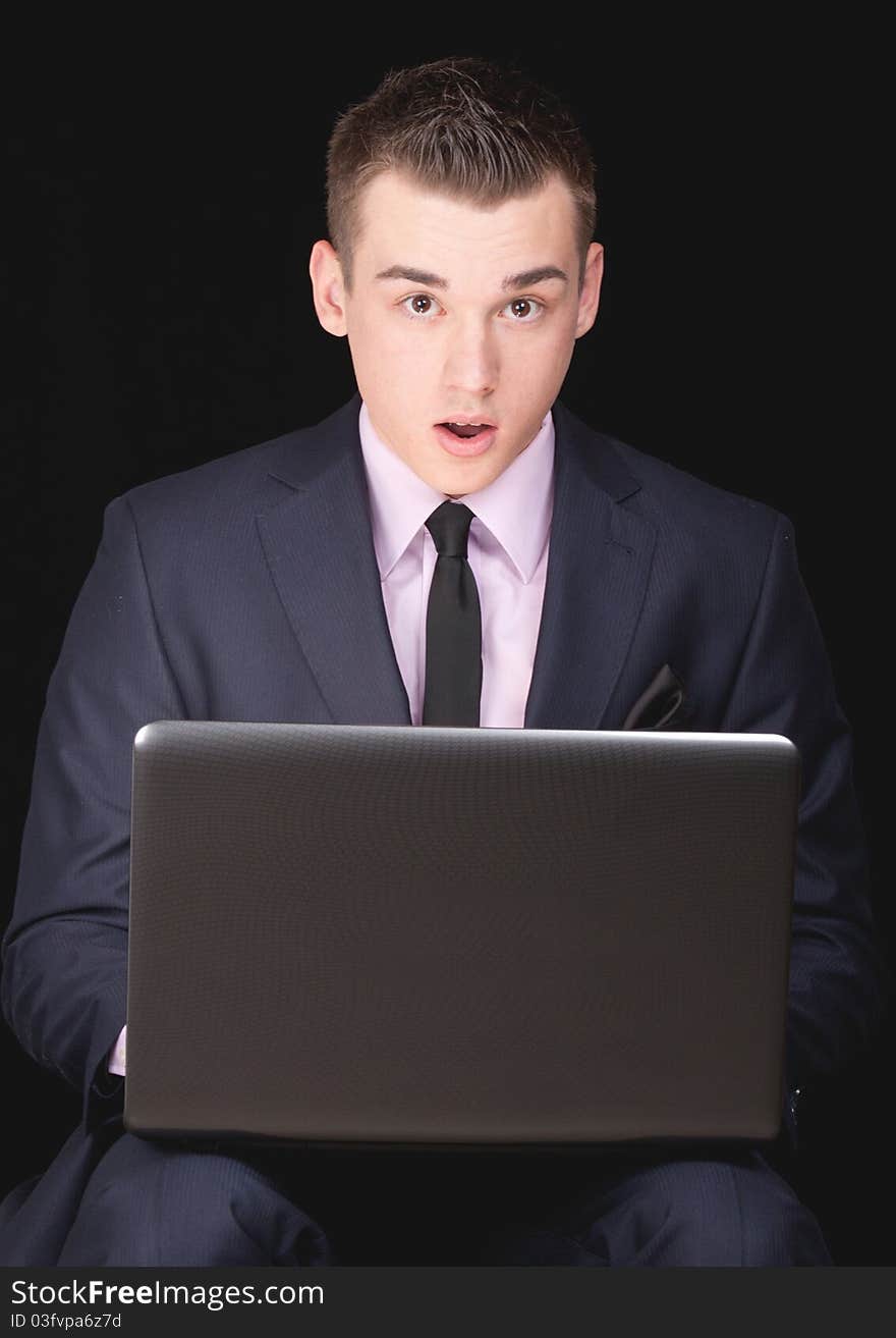 A photograph of a young executive who is excited by what he sees on his laptop computer. A photograph of a young executive who is excited by what he sees on his laptop computer.