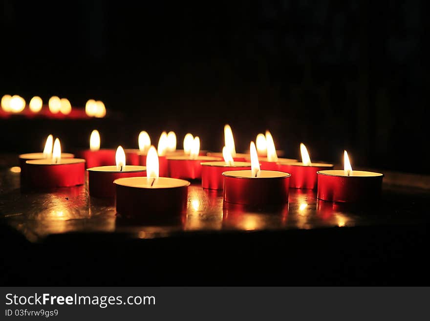 Several lighted red candles in the church