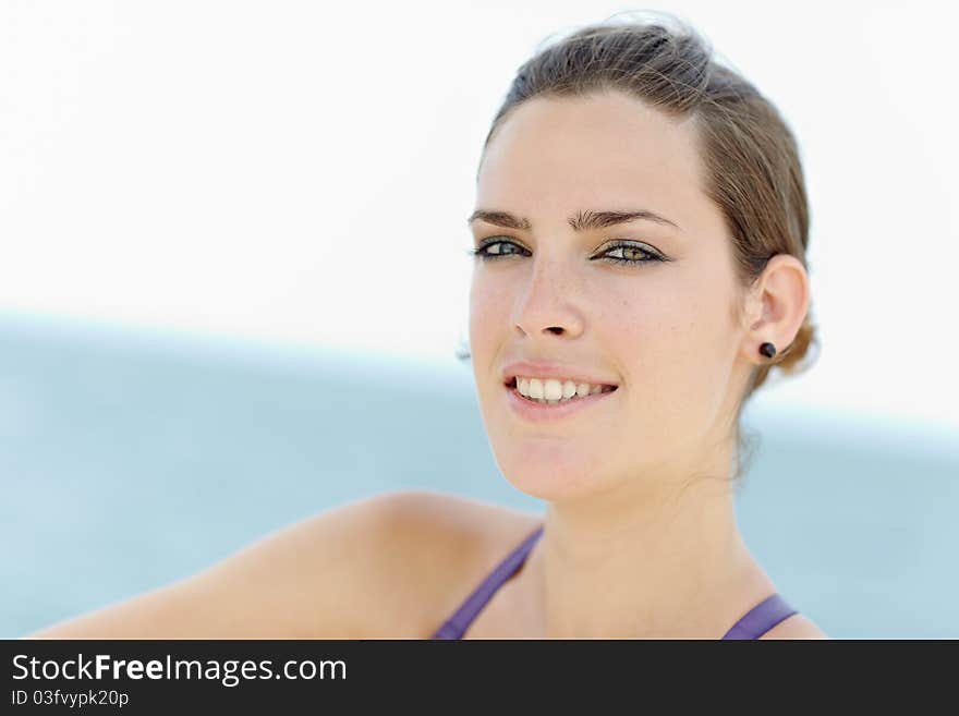 Portrait of young caucasian woman looking at camera near the sea. Horizontal shape, head and shoulders, copy space. Portrait of young caucasian woman looking at camera near the sea. Horizontal shape, head and shoulders, copy space