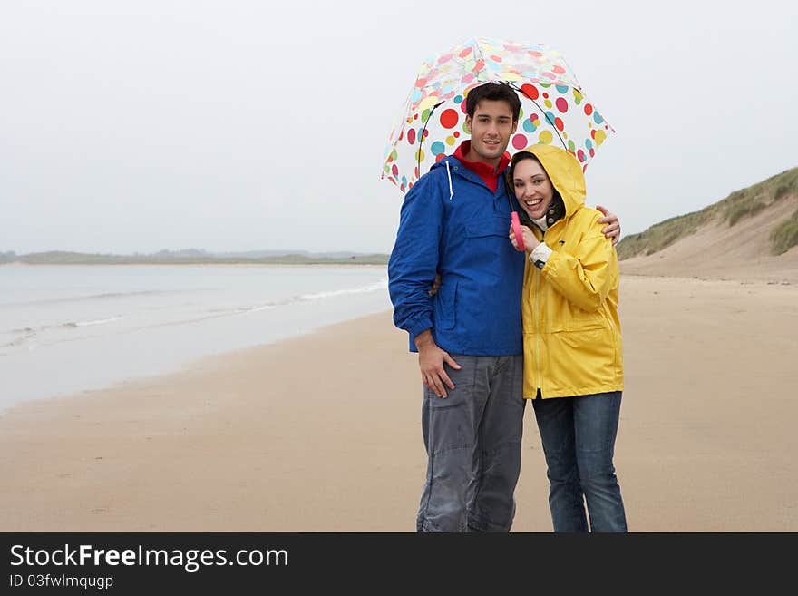 Young Couple On Beach With Umbrella