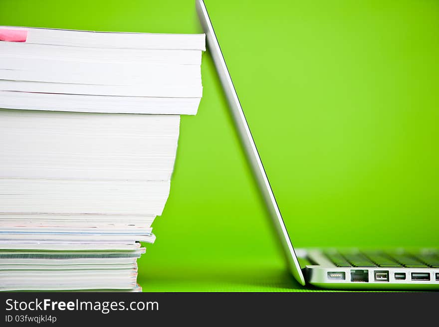 Stack of books and a laptop isolated over a green background. Stack of books and a laptop isolated over a green background